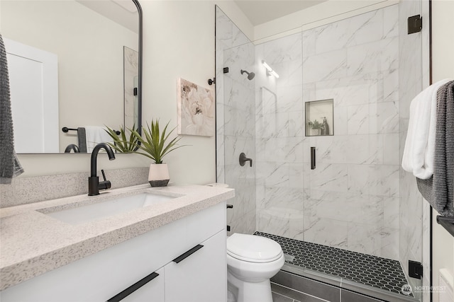 bathroom featuring vanity, toilet, and a shower with door