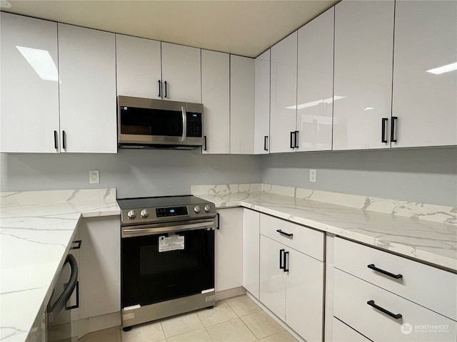 kitchen with white cabinetry, a skylight, light stone countertops, and stainless steel appliances