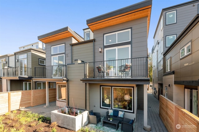 back of house with a balcony, a patio, and an outdoor living space