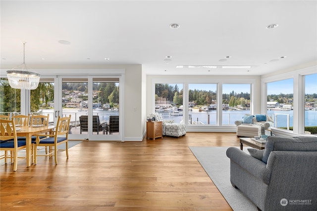 living room with an inviting chandelier, wood-type flooring, and a water view