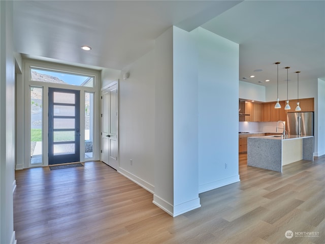 foyer entrance with light hardwood / wood-style floors and sink