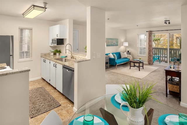 kitchen featuring appliances with stainless steel finishes, white cabinetry, sink, and light stone counters