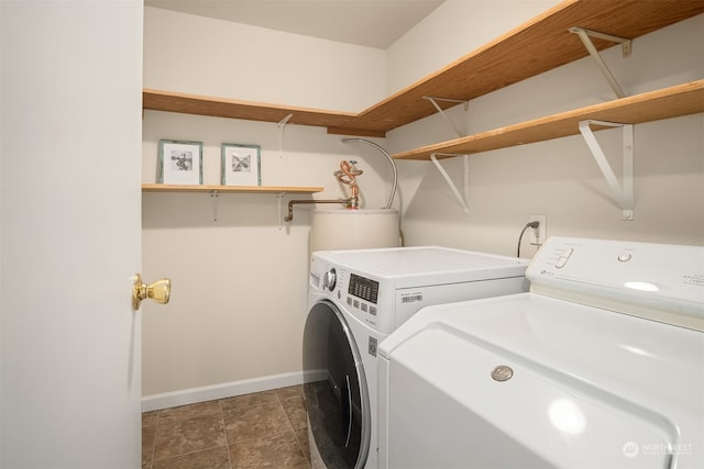 laundry area featuring water heater, separate washer and dryer, and dark tile patterned flooring