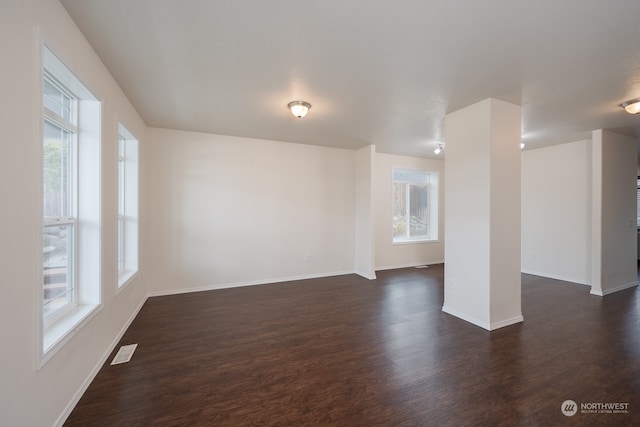 unfurnished living room featuring a wealth of natural light and dark wood-type flooring