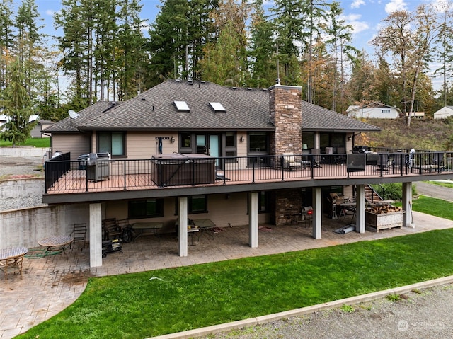 back of property featuring a deck, a yard, and a patio