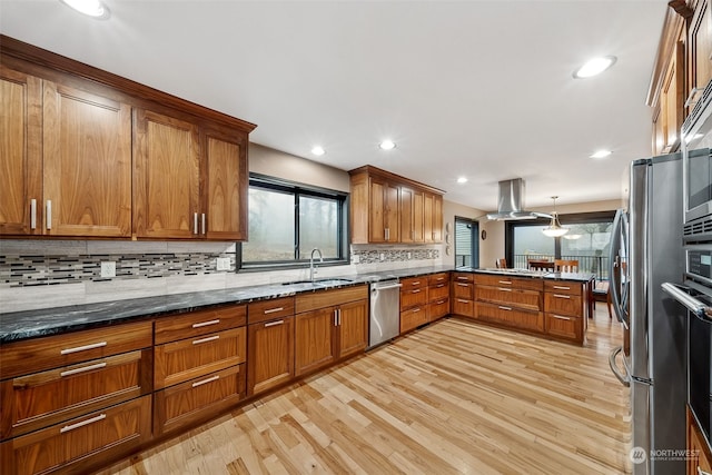 kitchen with sink, kitchen peninsula, light hardwood / wood-style floors, decorative light fixtures, and appliances with stainless steel finishes