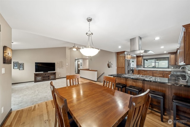 dining space with ceiling fan, light hardwood / wood-style floors, lofted ceiling, and sink