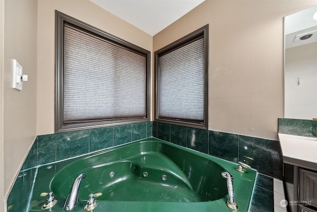 bathroom featuring tiled tub and vanity