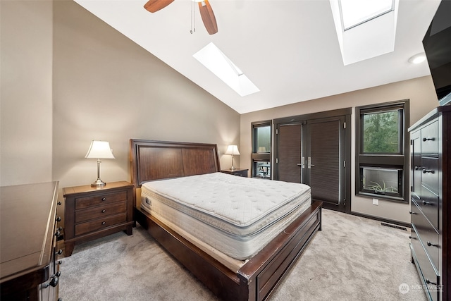 bedroom with light colored carpet, lofted ceiling with skylight, and ceiling fan