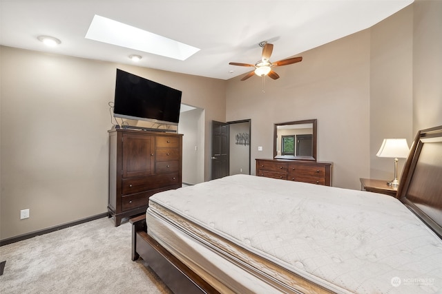 bedroom featuring light carpet, ceiling fan, and vaulted ceiling with skylight