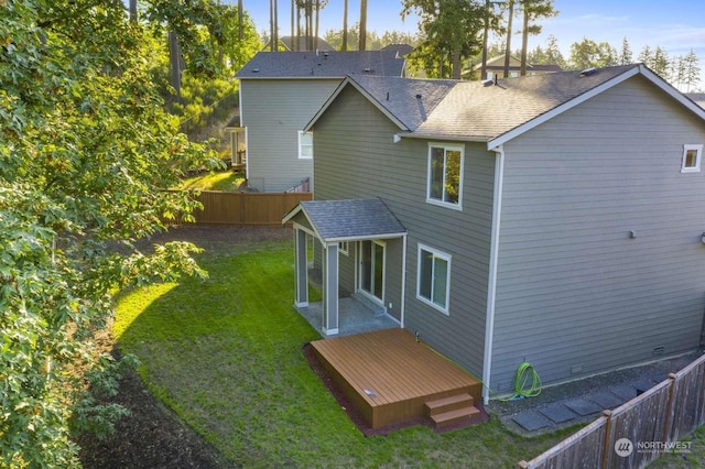 back of property with a wooden deck and a lawn