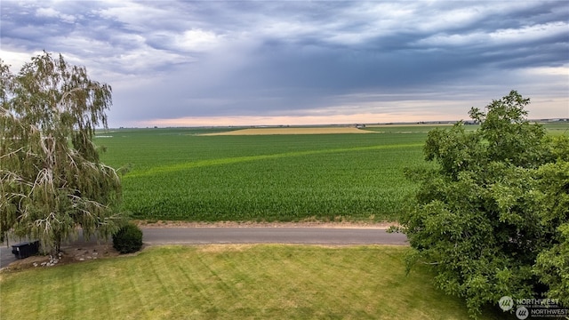 yard at dusk featuring a rural view