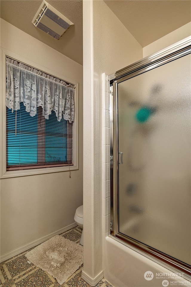 bathroom with tile patterned floors, combined bath / shower with glass door, and toilet