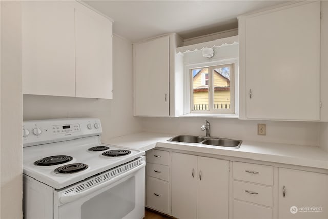 kitchen with white electric range oven, sink, and white cabinetry