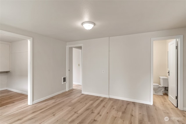 unfurnished bedroom featuring ensuite bathroom and light hardwood / wood-style flooring