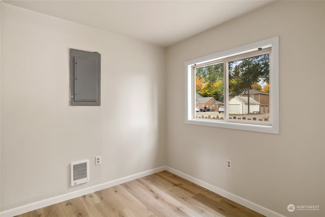 unfurnished room featuring light hardwood / wood-style flooring, electric panel, and heating unit