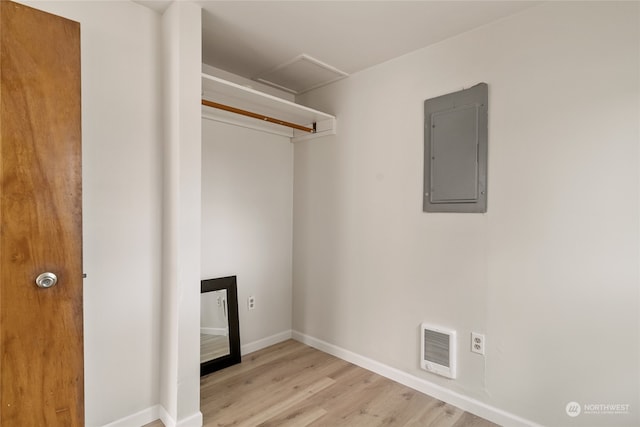 clothes washing area featuring light hardwood / wood-style flooring, electric panel, and heating unit