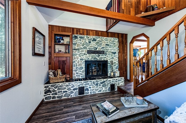 living room with hardwood / wood-style flooring, a stone fireplace, and beam ceiling