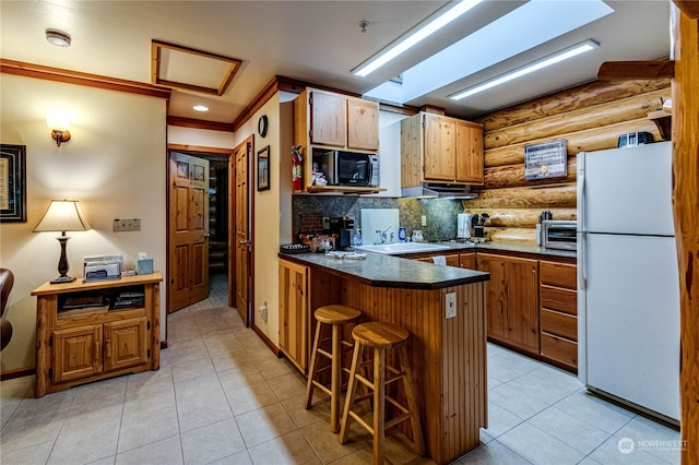 kitchen with a breakfast bar area, kitchen peninsula, light tile patterned floors, white fridge, and tasteful backsplash