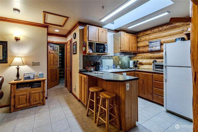 107 Dowans Creek Rd, Forks, WA 98331 - kitchen with freestanding refrigerator, a peninsula, log walls, black microwave, and a kitchen bar