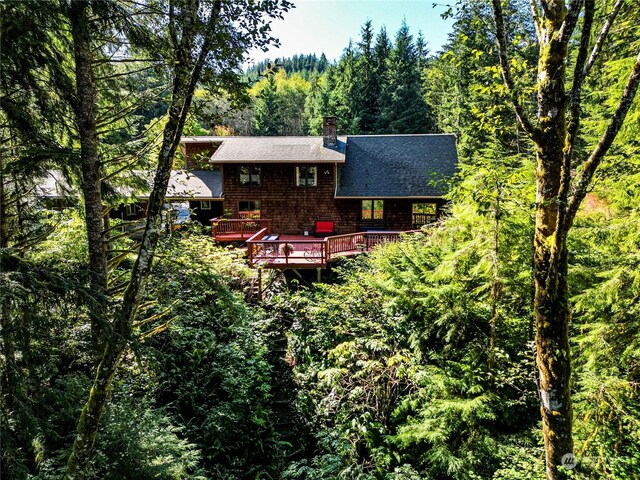 107 Dowans Creek Rd, Forks, WA 98331 - rear view of property with roof with shingles, a chimney, a forest view, and a wooden deck