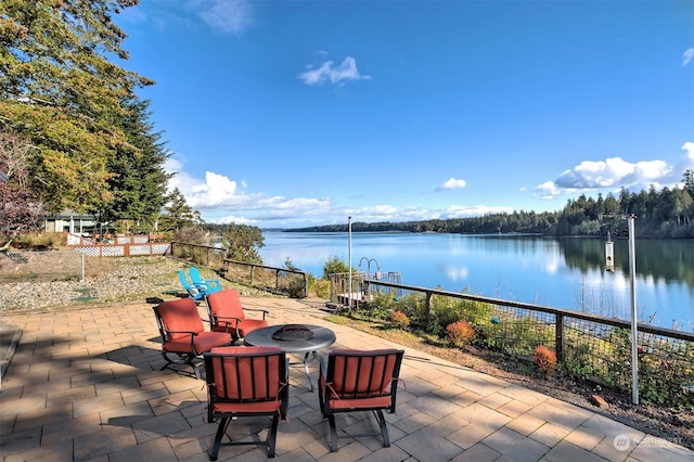 view of patio with fence, a water view, and an outdoor fire pit