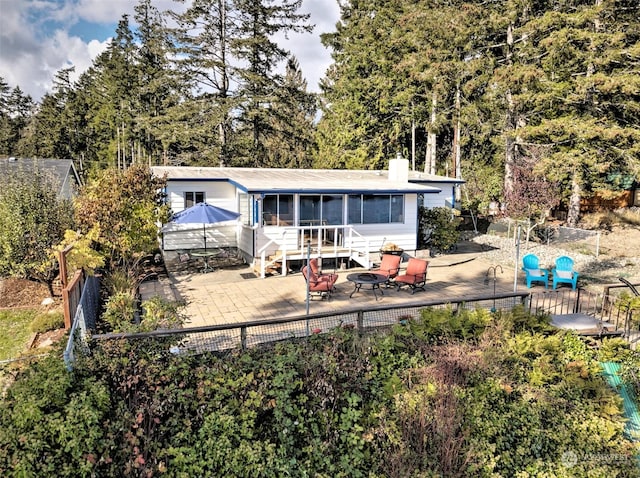rear view of property featuring fence, a chimney, a patio area, and a sunroom