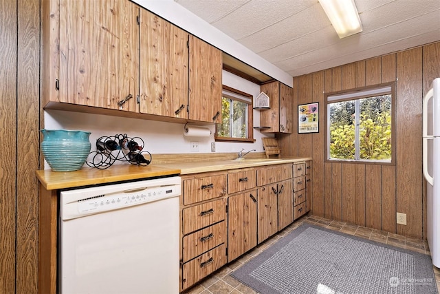 kitchen featuring white appliances, wooden walls, and light countertops