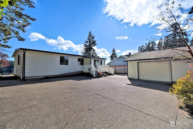 manufactured / mobile home featuring fence, driveway, an outdoor structure, and a garage