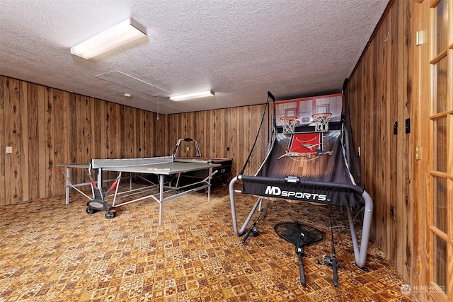 playroom featuring wooden walls and a textured ceiling