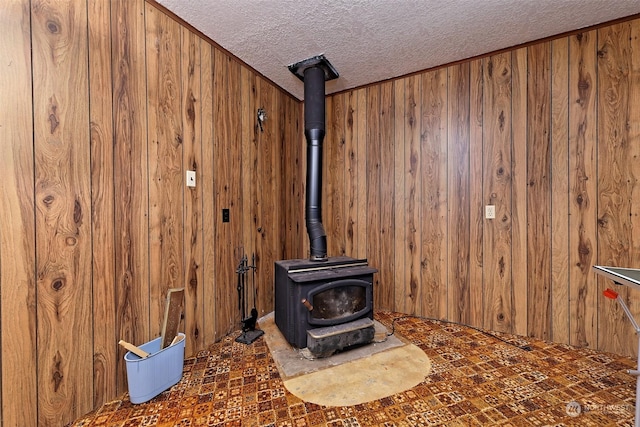 room details featuring a wood stove, wood walls, and a textured ceiling