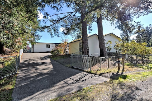 view of front facade with fence private yard, a gate, and aphalt driveway