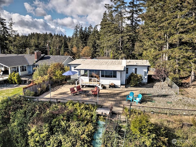 rear view of house featuring a forest view, a wooden deck, and a fenced backyard