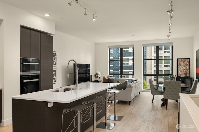 kitchen with a kitchen breakfast bar, light hardwood / wood-style flooring, sink, and an island with sink