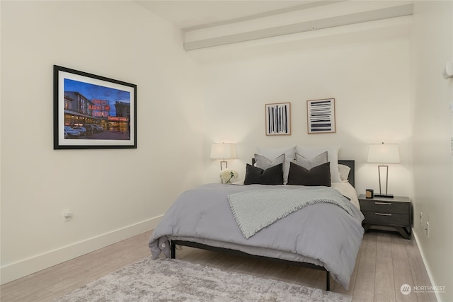 bedroom with beam ceiling and hardwood / wood-style flooring