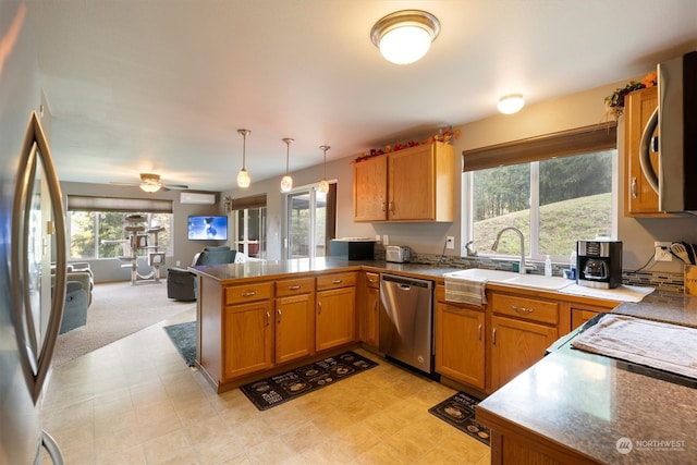 kitchen featuring a healthy amount of sunlight, appliances with stainless steel finishes, kitchen peninsula, and hanging light fixtures