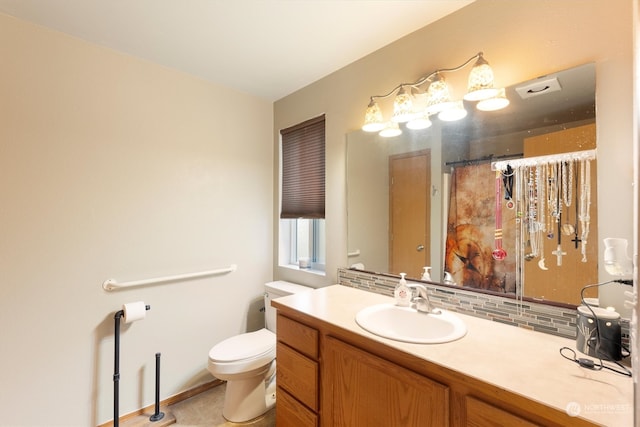 bathroom with vanity, toilet, and tasteful backsplash