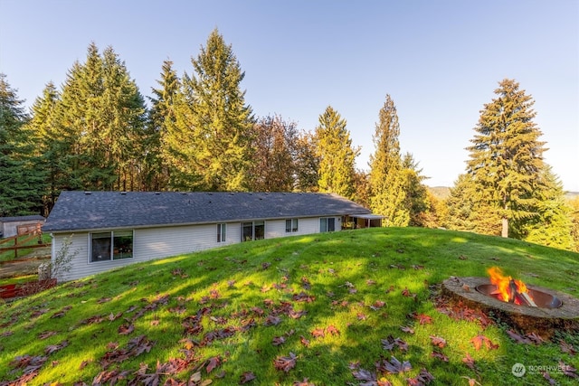 back of house featuring a lawn and a fire pit