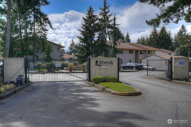 view of street featuring a gated entry, curbs, and a gate