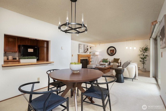 dining area with a chandelier, light colored carpet, and a fireplace