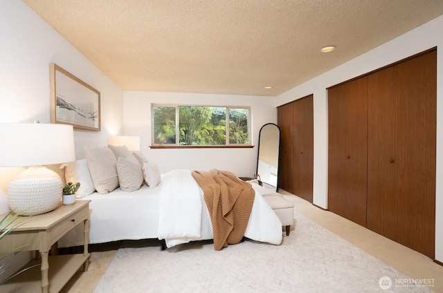 bedroom featuring recessed lighting, multiple closets, a textured ceiling, and light carpet