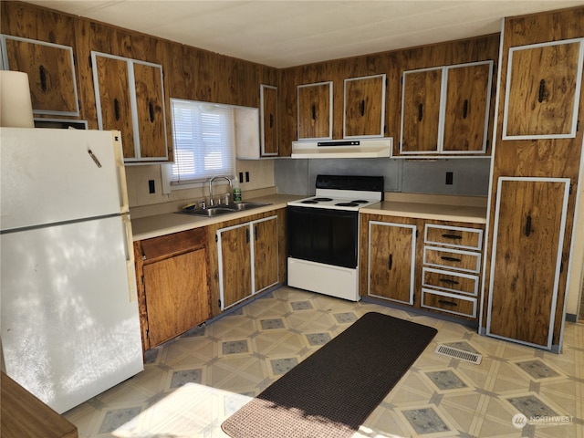 kitchen featuring wooden walls, sink, and white appliances