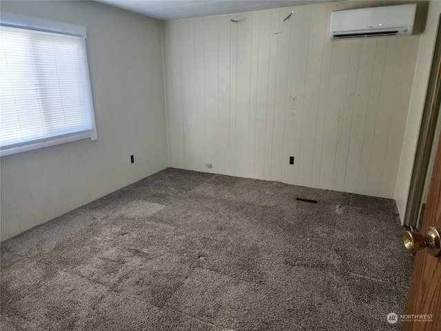 empty room with wooden walls, a wall unit AC, and carpet floors