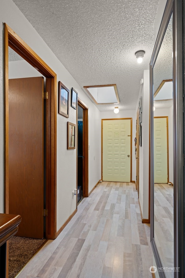 hallway with light hardwood / wood-style floors and a textured ceiling