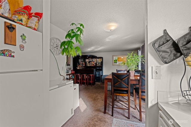 carpeted dining space with a textured ceiling