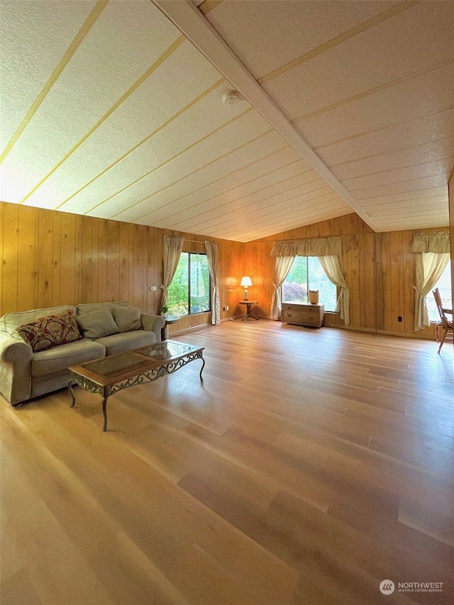 unfurnished living room with wood walls, wood-type flooring, and vaulted ceiling