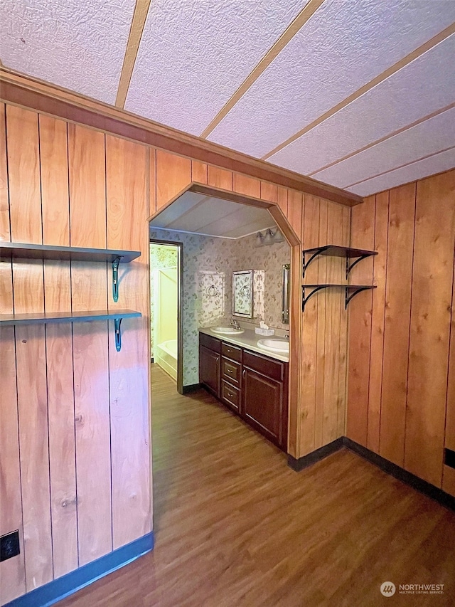 kitchen with wood walls, dark hardwood / wood-style floors, sink, and a textured ceiling