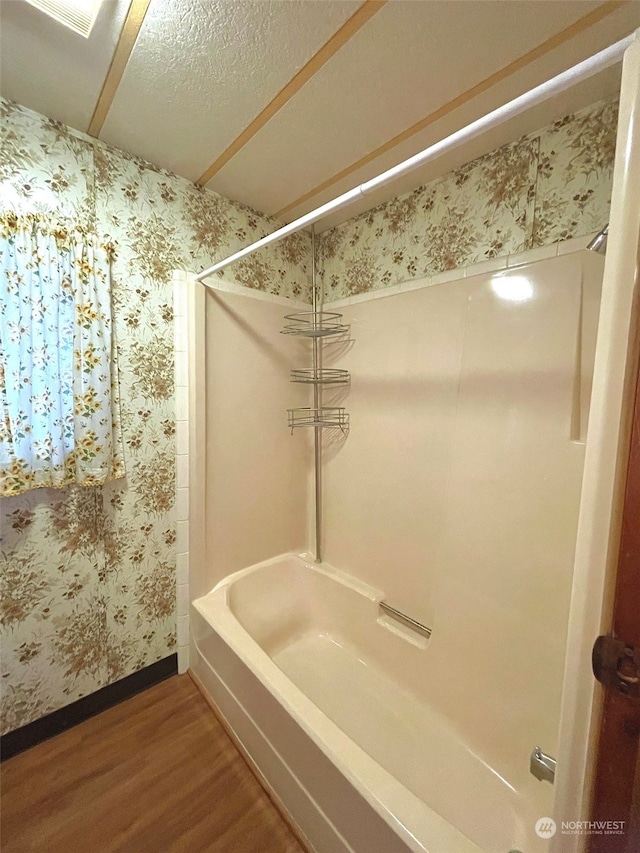 bathroom with hardwood / wood-style floors, a textured ceiling, and tub / shower combination