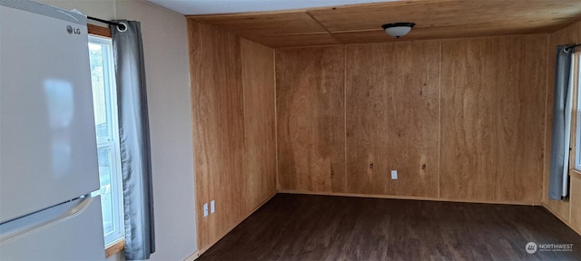 empty room featuring dark wood-type flooring and wooden walls