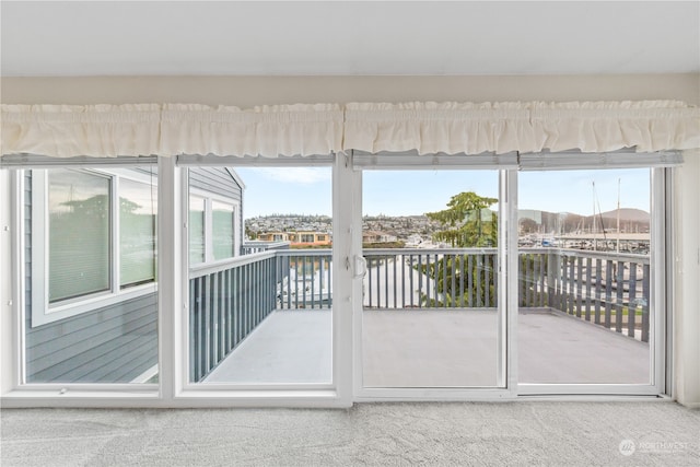 doorway to outside featuring a water view, a wealth of natural light, and carpet floors